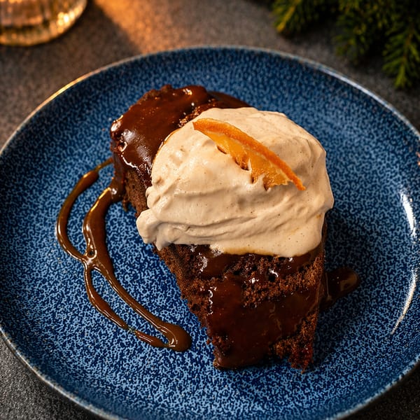 Chocolate cake with whipped cream and orange peel on a blue plate.